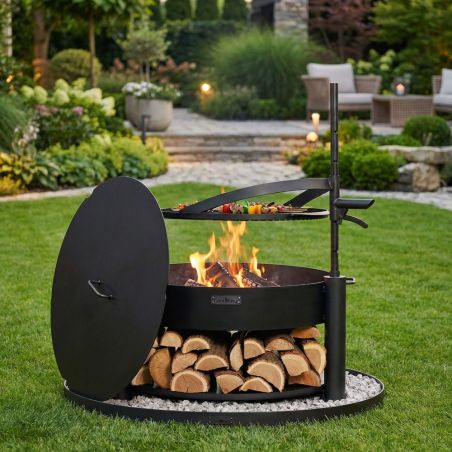 Brasero Cook King Montana X 80 cm avec grille et couvercle noir en extérieur, barbecue sur socle pierre et bûches rangées dessou