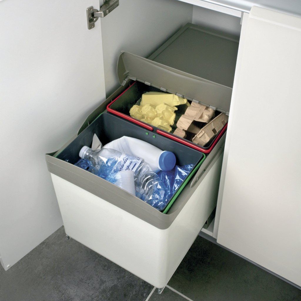 Caisse de rangement sous évier ouverte montrant des bacs de tri: plastique gris, anses vert et rouge, contenant bouteilles, gobelets et emballages. Caisse de rangement sous évier ouverte montrant des bacs de tri: plastique gris, anses vert et rouge, contenant bouteilles, gobelets et emballages.
