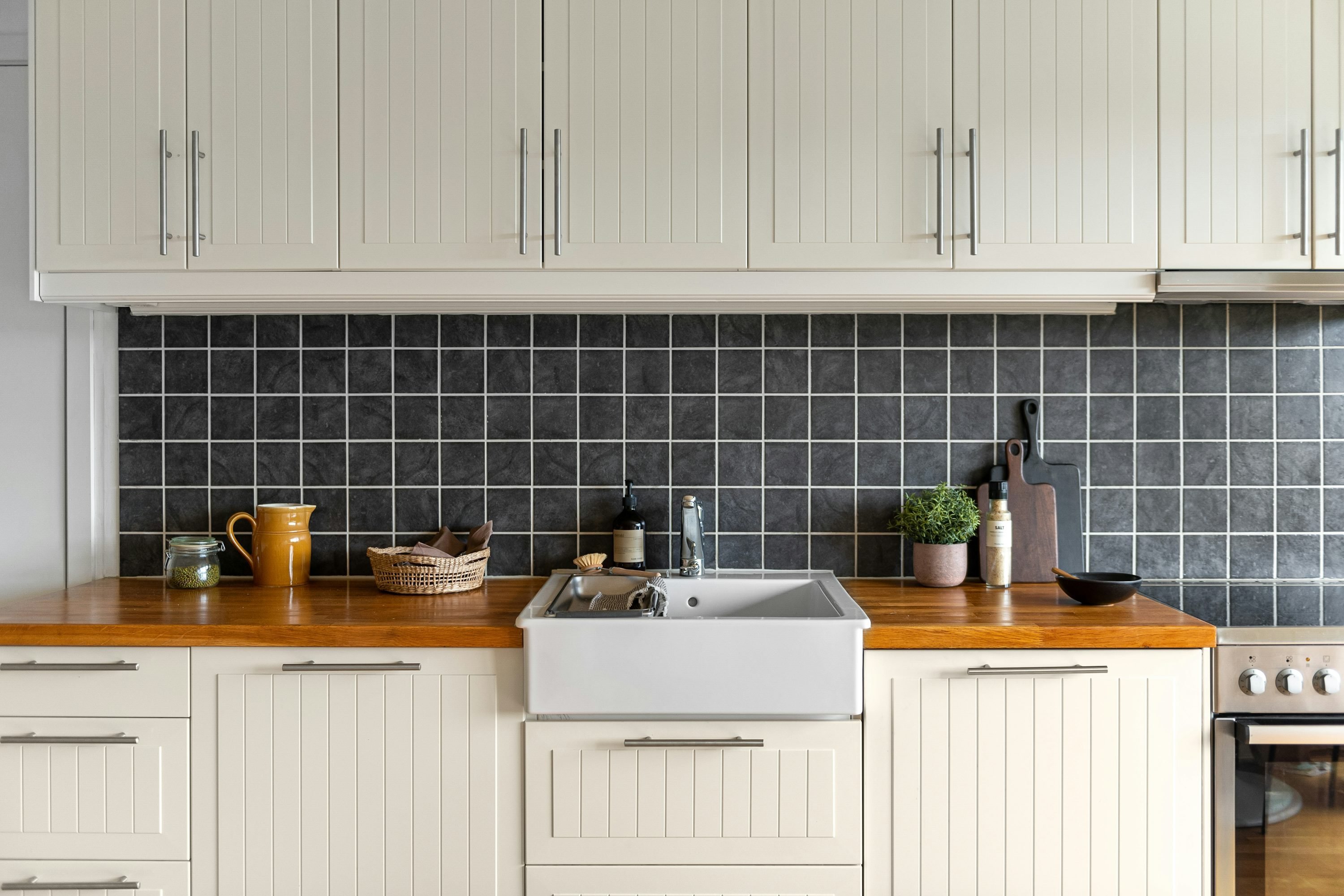 Cuisine contemporaine avec évier intégré, plan de travail en bois et crédences gris foncé à motifs carreaux.