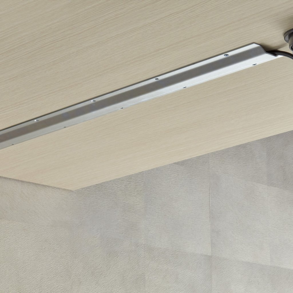 Rail de porte coulissante fixé sous plafond avec câble d’alimentation, vue du plafond et du mur.